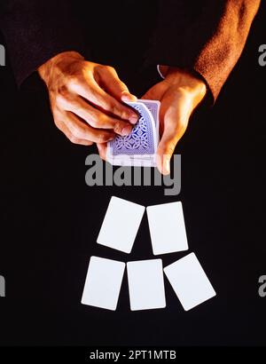 Ein Paar Hände und Spielkarten mit leeren Karten im Vordergrund Stockfoto