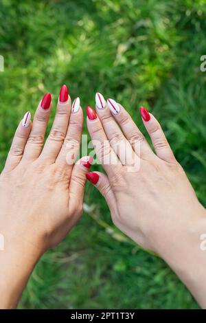 Das Mädchen zeigt eine schlechte alte Maniküre. Überwucherter Nagellack, gebrochener Nagel. Maniküre Korrektur, alte Maniküre. Nagelpflege, es ist Zeit, in den Salon zu gehen Stockfoto