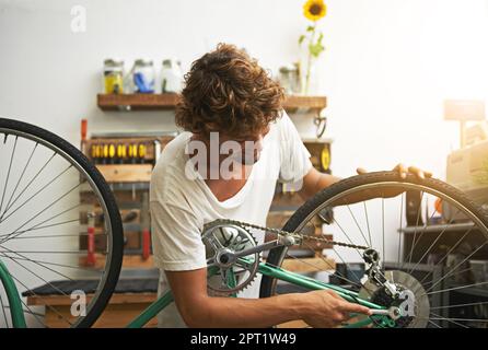 Er kennt sich mit dem Fahrrad aus. Ein junger Fahrrad-Reparateur in einer Werkstatt Stockfoto