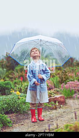 Mein Garten liebt den Regen. Die volle Länge eines jungen Mannes, der draußen im Regen steht Stockfoto