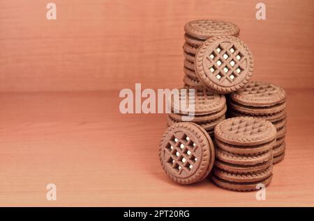 Haufen Chocolate Chip Cookies mit Weiße Vanille Creme gefüllt liegt auf Holz- braune Oberfläche. Süßes und leckeres Sandwich runde Kekse. Detaillierte essen Ph Stockfoto