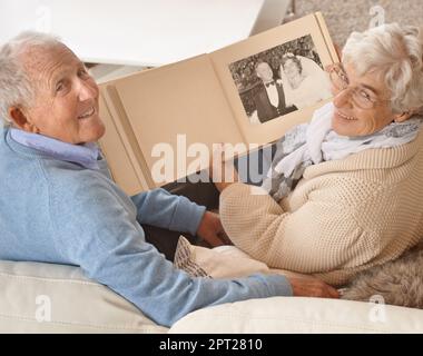 Es war der perfekte Tag. Ein Seniorenpaar blättert durch ihr Hochzeitsalbum Stockfoto