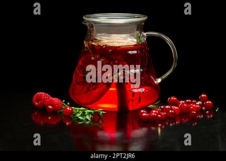 Beerentee mit frischen Johannisbeeren, Himbeeren und Erdbeeren. Teekanne mit Früchten und Beeren. Stockfoto