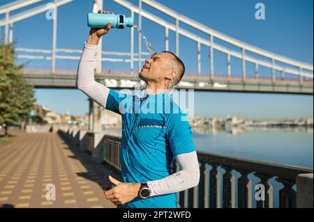 Müder Läufer gießt Wasser auf sein Gesicht, um sich nach intensivem Training abzukühlen. Gesundheit, Lauftraining und Fitnesskonzept Stockfoto