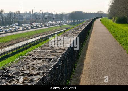 Rotterdam, Niederlande, 5. April 2023: Fußweg auf der Schallmauer mit Blick auf die Autobahn A20, mit Stau in beide Richtungen Stockfoto