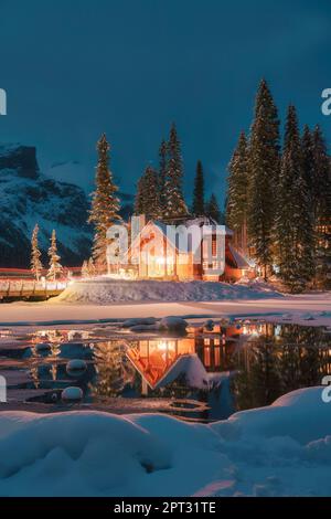 Wunderschöner Blick auf den Emerald Lake mit einer Holzhütte, die im Winter im schneebedeckten Kiefernwald im Yoho-Nationalpark, Alberta, Kanada, glüht Stockfoto