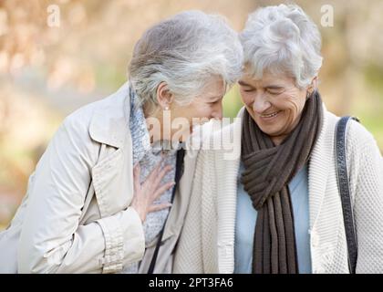 Sie sind immer noch beste Freunde. Kurzer Blick auf zwei Seniorinnen, die im Freien lächeln und sich unterhalten Stockfoto