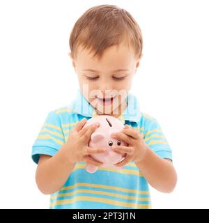 Es fühlt sich so voll an. Studiofoto eines kleinen Jungen, der auf ein weißes Sparschwein schaut Stockfoto