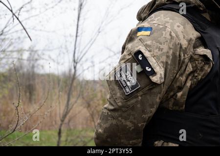 Neben einer ukrainischen Flagge in der ukrainischen Position in der Nähe von Bakhmut befindet sich auf der Uniform eines ukrainischen Soldaten ein Pflaster mit der Aufschrift „Hör auf zu schreien, dass ich auch Angst habe“. Die ukrainischen Streitkräfte kämpfen in Bakhmut und der Umgebung intensiv, da die russischen Streitkräfte immer näher an die Übernahme der Oststadt der Ukraine heranrücken. Die Schlacht von Bakhmut ist heute als „der blutigste“ und „einer der längsten Schlachten“ bekannt und hat sich zu einem der bedeutendsten Kämpfe im Krieg zwischen der Ukraine und Russland entwickelt. Stockfoto