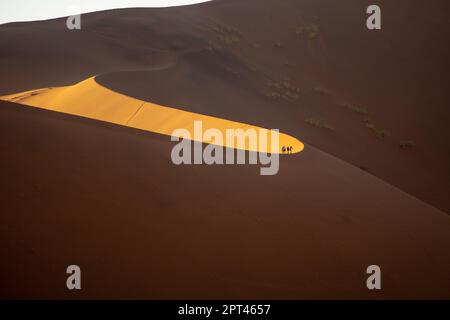 Touristen klettern auf Sanddünen, Sossusvlei, Namib-Wüste, Namib-Naukluft Park, Namibia Stockfoto