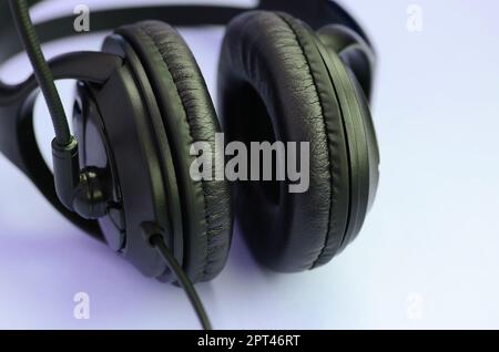 Schwarz Kopfhörer liegt auf einer bunten Pastell violett unterlegt. Musik Konzept Stockfoto