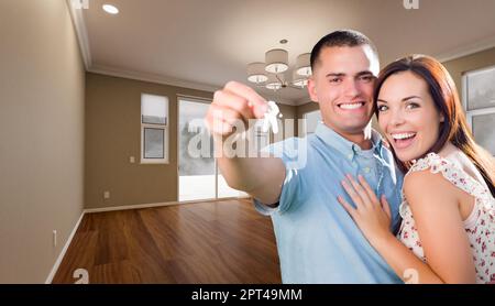 Junge militärische Paar mit Hausschlüssel im leeren Raum der neuen Heimat. Stockfoto