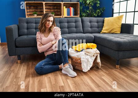 Junge Frau, die zu Hause Wäsche waschen möchte, ist unglücklich Stockfoto