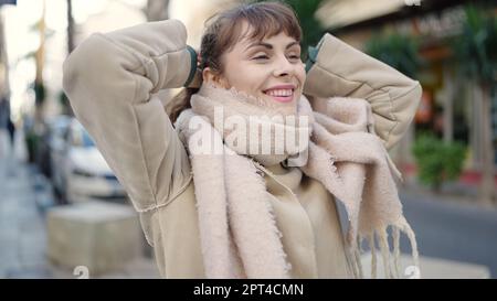 Junge weiße Frau, die lächelt und auf der Straße einen Pferdeschwanz mit Haaren macht Stockfoto