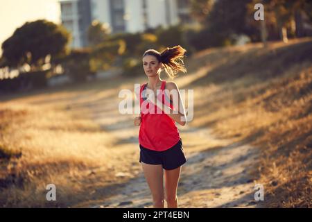 Sie gibt ihr alles bei jedem Lauf. Eine sportliche junge Frau, die draußen Sport treibt Stockfoto