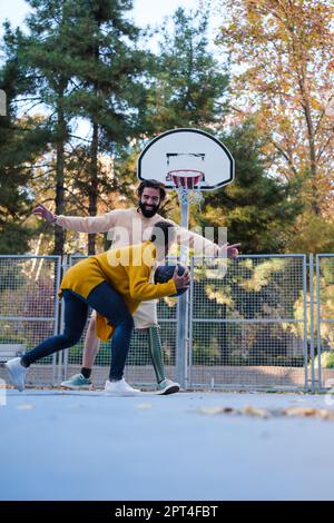 Junge Frau mit Beinprothese, die mit ihrer Freundin Basketball spielt und draußen Spaß hat. Konzept: Lifestyle, Sport, Verbesserung Stockfoto