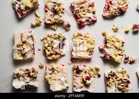 Gesundes gefrorenes griechisches Joghurt mit Erdbeere mit Limettenschale, Nüssen und weißer Schokolade. Hausgemachtes süßes Dessert auf weißem Marmorhintergrund. Draufsicht Stockfoto