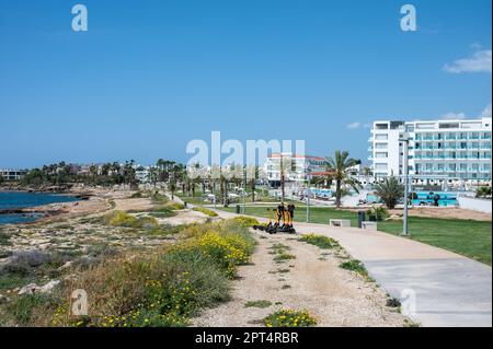 Coral Bay, Zypern, 25. März 2023 - Ferienresort mit Betonwanderweg am Strand Stockfoto