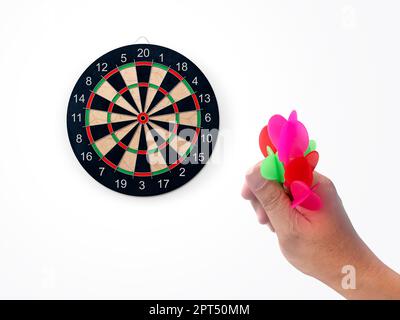 Die menschliche Hand wirft die Zielscheibe des Darts auf das Darts-Brett. Die Hand eines Mannes wirft einen Pfeil auf das Ziel Stockfoto