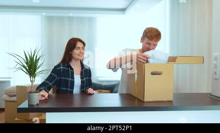 Porträt eines jungen Paares, das in einem neuen Zuhause zusammenlebt. Ein paar packen Sachen aus dem Pappkarton aus, nachdem sie in eine neue Wohnung gezogen sind. Glückliche Ehepartner Stockfoto