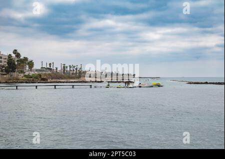 Paphos, Zypern - 27. März 2023 - die Küste mit Wassersportaktivitäten am Strand Stockfoto