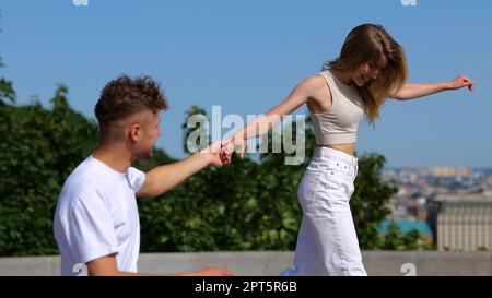 Ein fröhliches junges weißes Paar, Mann und Frau, die in der Stadt spazieren und lachen und den Tag zusammen verbringen. Glück. Freund und Freundin, die draußen verliebt sind Stockfoto