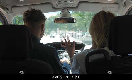Das junge Paar, das im Auto sitzt und zusammen verreist. Rückblick auf die kaukasische fröhliche Freundin, die während der Reise Spaß im Auto hat Stockfoto