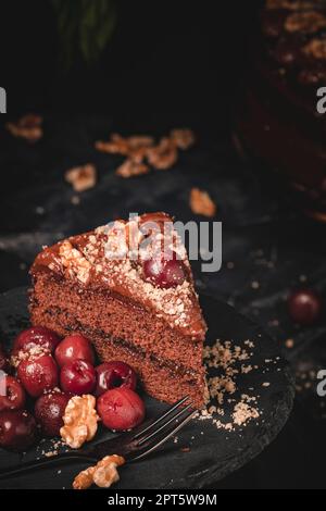 Schokoladenkuchen mit Nüssen und Kirschen, ein Stück Kuchen, Studiofoto, Essensfotografie, Stillleben Stockfoto