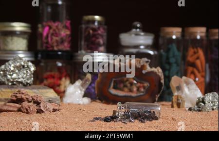 Flasche Chakra-Steine auf rotem Sand mit agatisierter Koralle im Hintergrund mit flachem Innengewinde Stockfoto