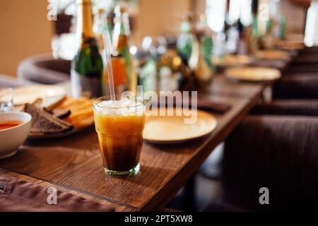 Eiskaffee mit Orange. Ein Glas Amerikanicano mit Limonade und Yuzu-Orangensaft auf verschwommenem Hintergrund, erfrischendes Sommergetränk-Konzept Stockfoto