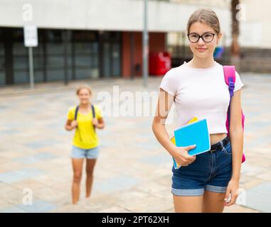 Mädchen mit Copybooks, die neben dem Schulgebäude stehen Stockfoto