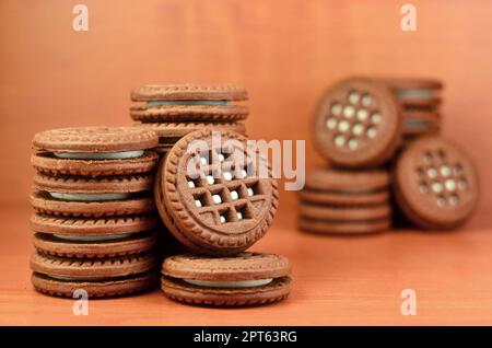 Haufen Chocolate Chip Cookies mit Weiße Vanille Creme gefüllt liegt auf Holz- braune Oberfläche. Süßes und leckeres Sandwich runde Kekse. Detaillierte essen Ph Stockfoto