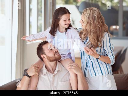 Ein bezauberndes kleines Mädchen, das sich mit ihren Eltern zu Hause amüsiert. Sorgenfreie Kaukasier-Familienbande und Zeit miteinander verbringen. Tochter spielt mit Mo Stockfoto