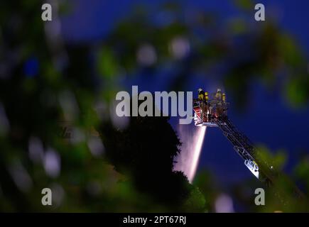 Dresden, Deutschland. 27. April 2023. Feuerwehrleute löschen einen Brand in einer Wäscherei im Bezirk Pieschen über eine Luftleiter. Kredit: Robert Michael/dpa/Alamy Live News Stockfoto