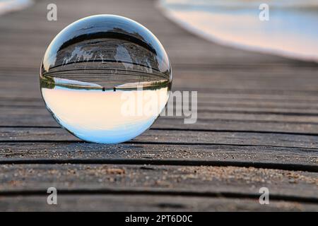 Glasball auf einem hölzernen Pier an einem schwedischen See zur Abendstunde. Natur aus Skandinavien Stockfoto