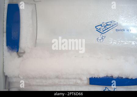 Frostbildung im Gefrierschrank. Eis aushärten, indem es aus der Gefriertür gedrückt wird. Stockfoto