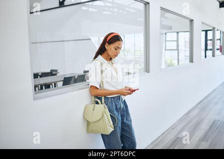 Mädchen, Student und Telefon im College nach Klassenfenster in der Universität für E-Mail, Lernen oder soziale Medien. Frau, Ausbildung und Smartphone für die Kommunikation Stockfoto