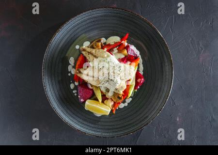 Gebratenes Fischfilet mit gegrillte rote Beete, Karotten, Paprika, Zucchini, auf dunklem Hintergrund Knoblauch Stockfoto