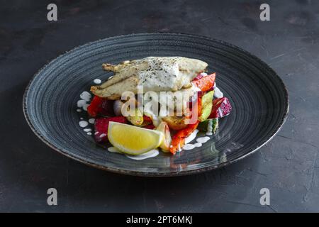 Gebratenes Fischfilet mit gegrillte rote Beete, Karotten, Paprika, Zucchini, auf dunklem Hintergrund Knoblauch Stockfoto