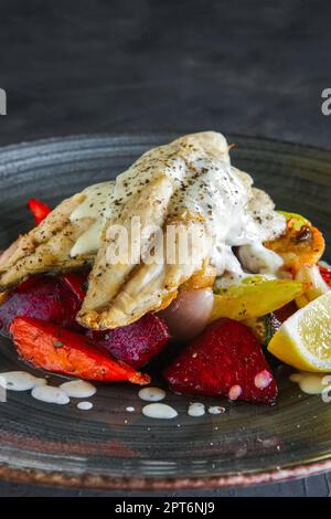 Gebratenes Fischfilet mit gegrillte rote Beete, Karotten, Paprika, Zucchini, auf dunklem Hintergrund Knoblauch Stockfoto
