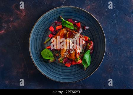 Blick von oben auf die gebratenen Zander mit roter Bete, Karotten, Brokkoli und Balsamico Sauce serviert. Stockfoto