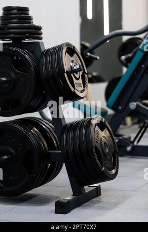 Moderne Scheiben für Langhantel im Fitnessstudio. Schwarze Hantelscheiben aus Metall für Langhantel befinden sich auf dem Gestell im Sportkomplex. Konzept der Fitnessgeräte. Nahaufnahme. Stockfoto