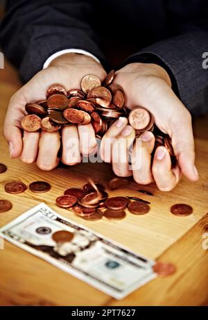 Jeder Penny zählt. Nahaufnahme von Händen, die Münzen halten, mit einem Schein auf dem Tisch Stockfoto