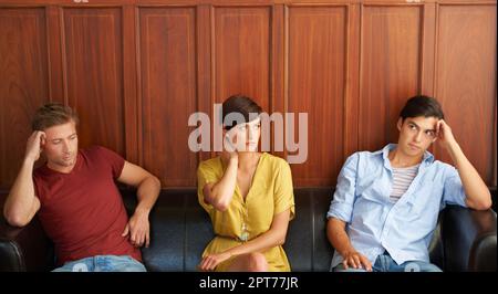 Wir haben lange gewartet. Porträt von drei gelangweilten jungen Leuten, die auf dem Sofa sitzen Stockfoto