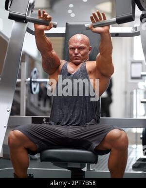 Wunderschön gebaut. Ein männlicher Bodybuilder mit Trainingsgeräten im Fitnessstudio Stockfoto