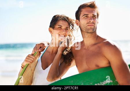 Die Leidenschaft für das Surfen teilen. Ein junges Paar, das zusieht, bevor es zum Surfen geht - Copyspace Stockfoto