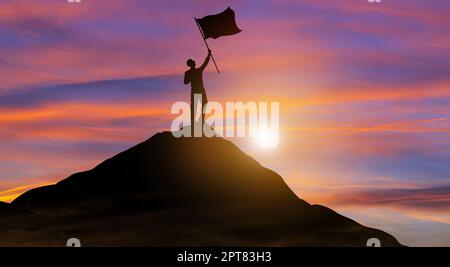 Silhouette Geschäftsmann mit Flagge kletterte auf die Spitze des Berges über den Himmel und Sonnenlicht Hintergrund. Erfolg, Zielerreichung, Führung und Busine Stockfoto