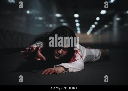 Horror asiatische Frau Zombie mit Blut gruselig kriechen bewegen langsam kriechen, gruselige Geist zerrissene Haare bedeckt ihr Gesicht mit Blut in der Hand erreichen ou Stockfoto