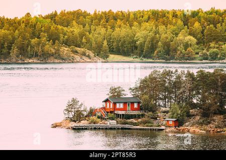 Schweden. Im Sommer Gibt Es Viele Schöne Rote Schwedische Holzhütten An Der Rocky Island Küste. See- Oder Flusslandschaft. Stockfoto