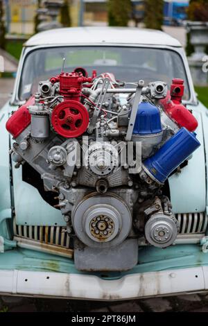 Bild eines getunten Oldtimers mit einem großen Motor, der aus der Motorhaube ragt. Stockfoto